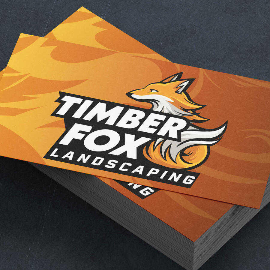 A stack of orange business cards featuring the Timber Fox Landscaping logo. The logo is a sharp, almost sports-team style fox, with high contrast text.